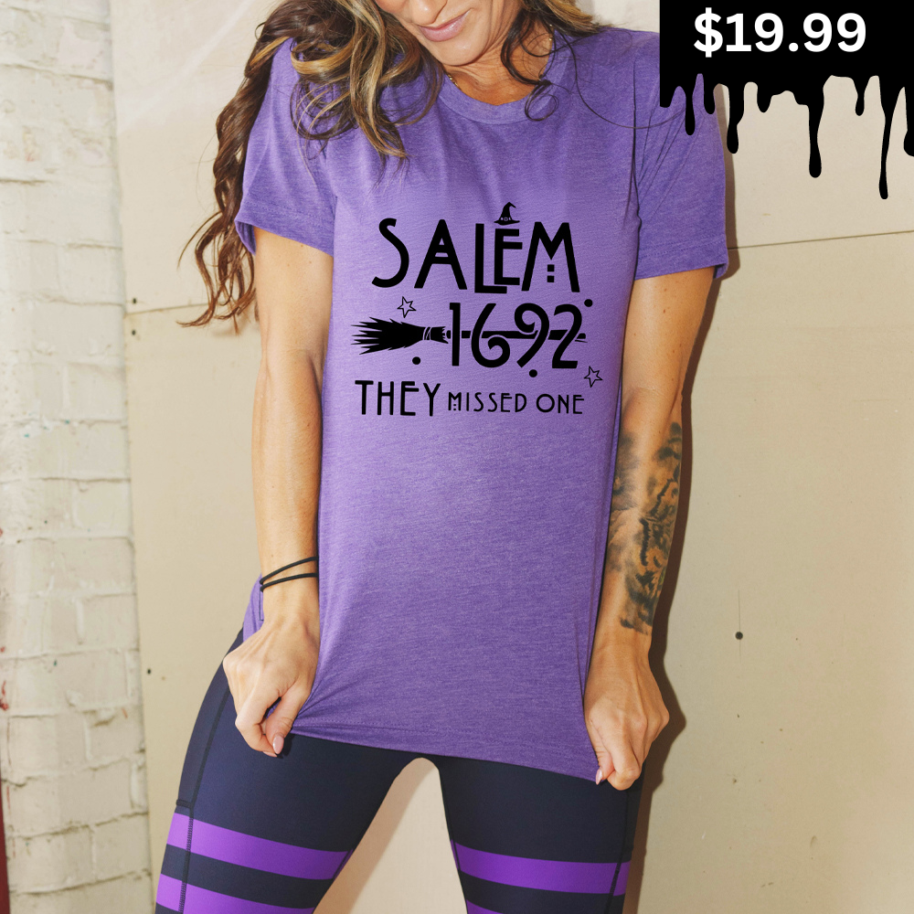 model wearing a purple unisex tee with the saying "salem 1692 they missed one" - on sale for $19.99