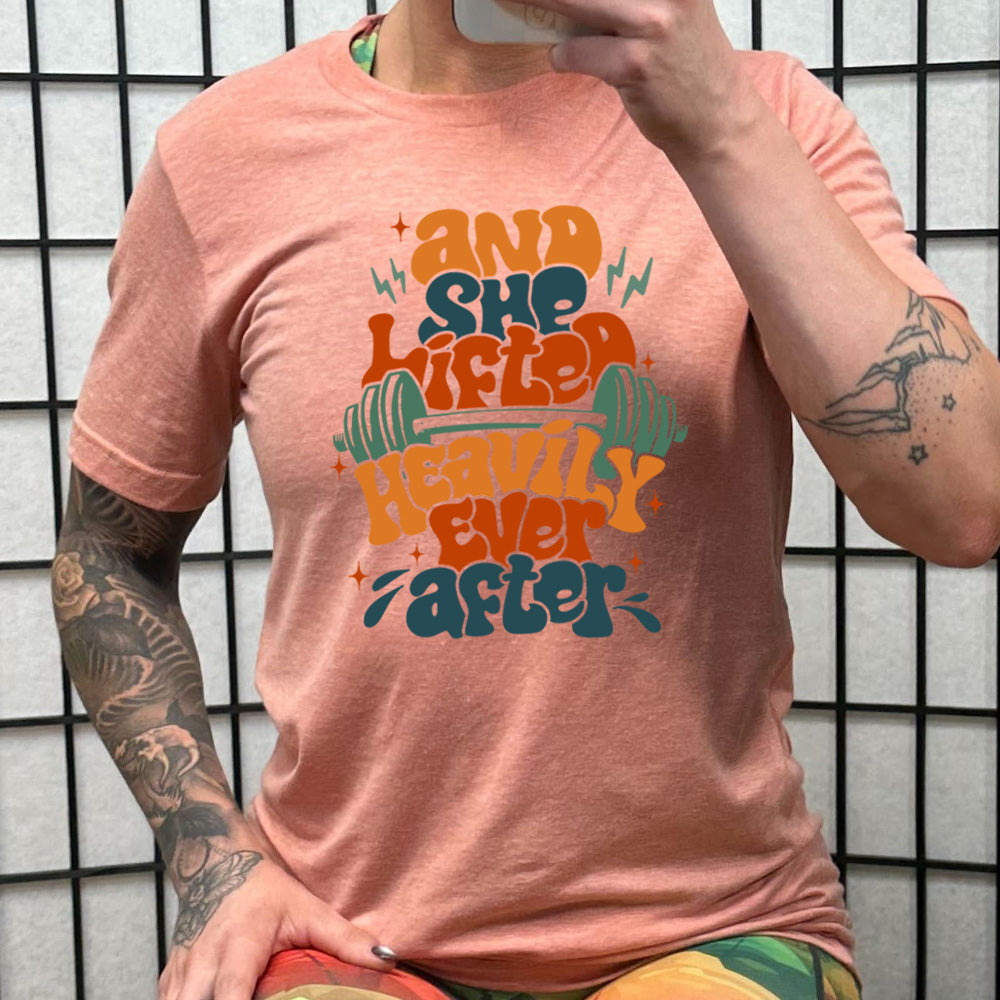 peach shirt with the text "And She Lifted Heavily Ever After" on it