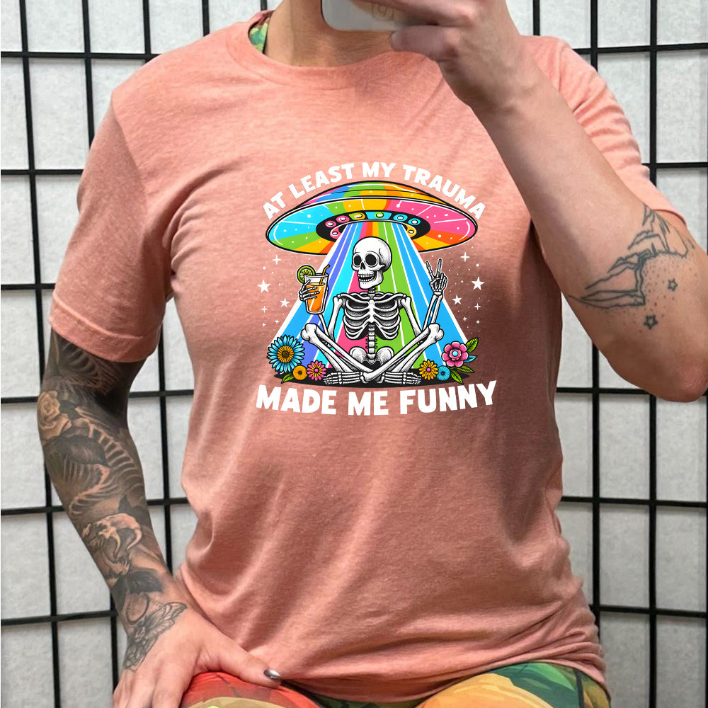 peach shirt with the text "At Least My Trauma Made Me Funny" on it