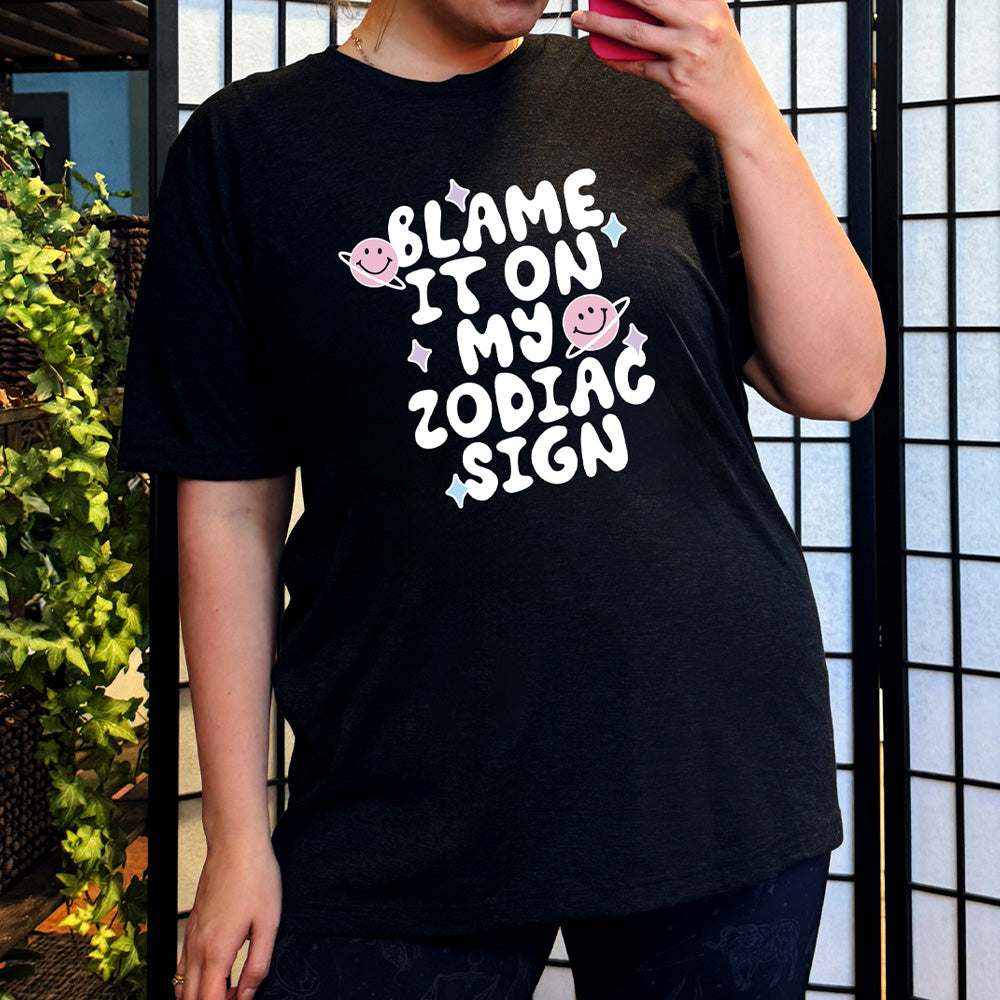 black shirt with the text "Blame It On My Zodiac Sign" on it