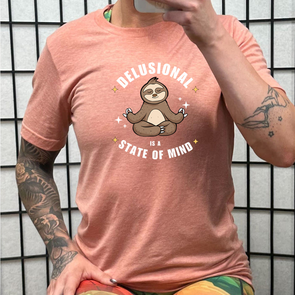 peach shirt with the quote "Delusional Is A State Of Mind" on it