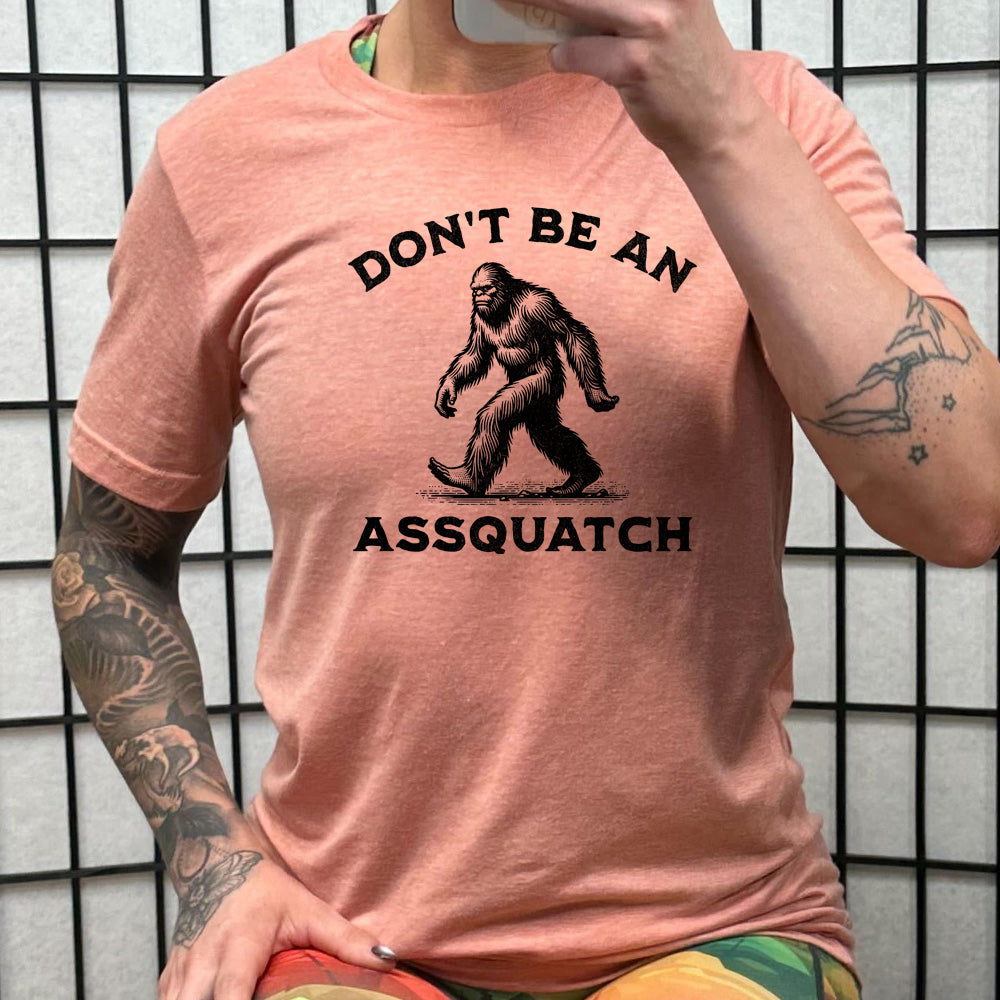 peach shirt with the text "Don't Be An Assquatch" on it