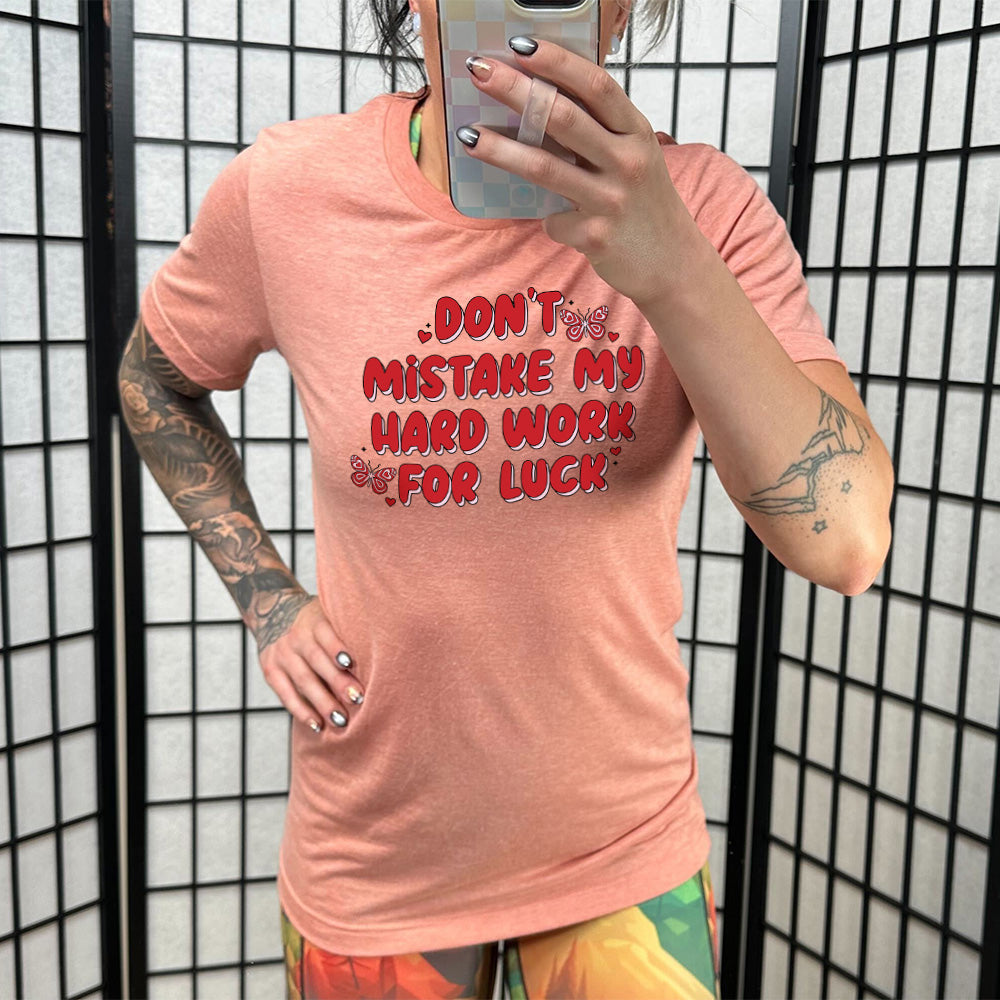 coral unisex shirt with the text "Don't Mistake My Hard Work For Luck" on it