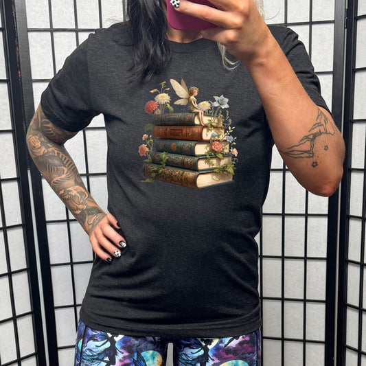 black shirt with a fairy sitting on books graphic in the center