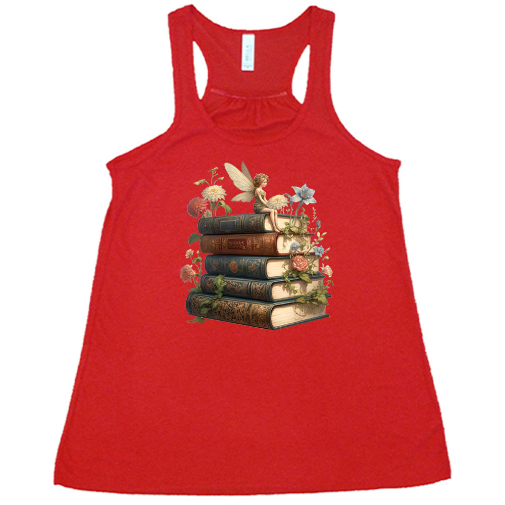 red shirt with a fairy sitting on books graphic in the center