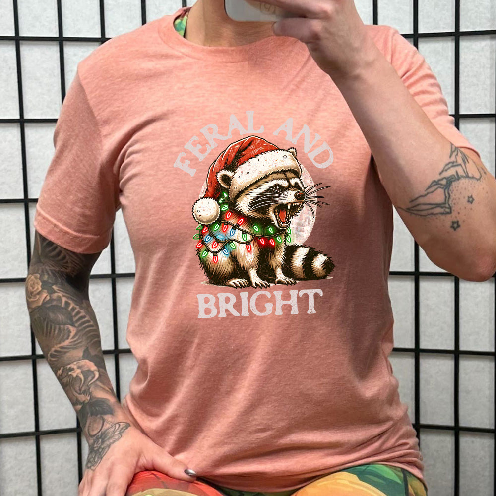 peach shirt with the text "Feral And Bright" with a raccoon graphic on it