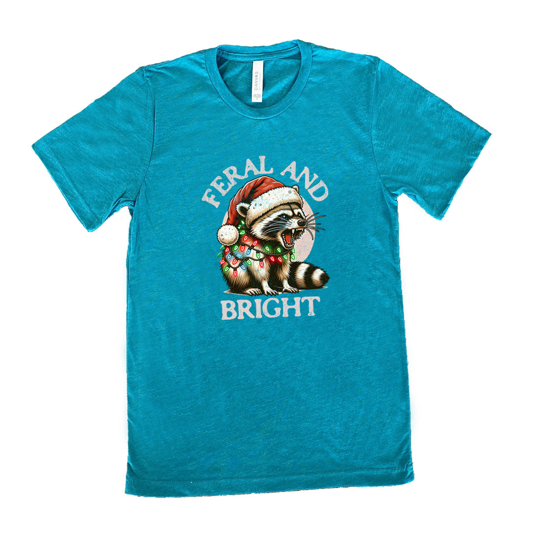 teal shirt with the text "Feral And Bright" with a raccoon graphic on it