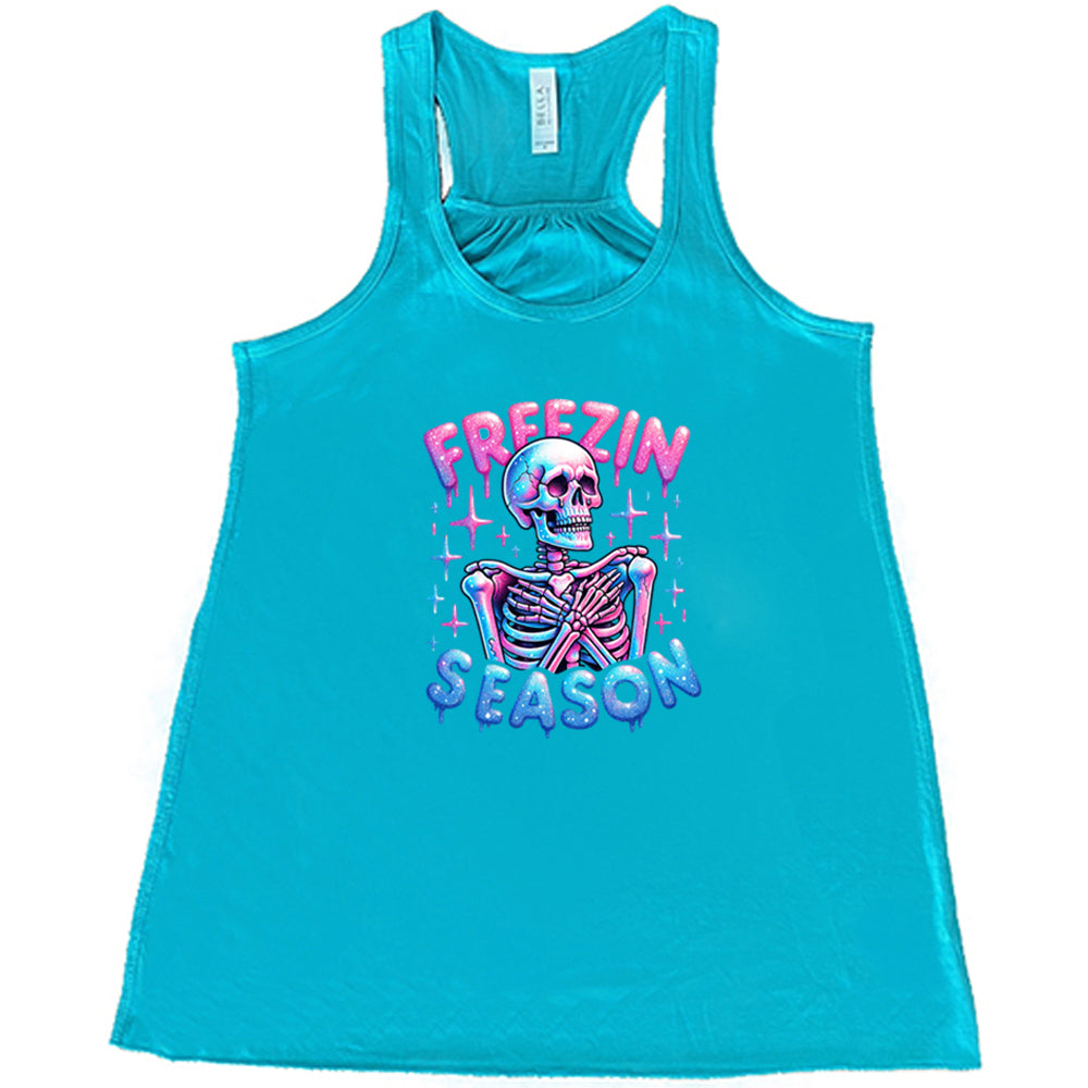 teal shirt with the text "freezin season" with a graphic of a skeleton on it