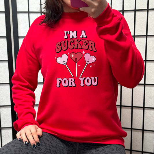 red crewneck with the text "I'm A Sucker For You" on it