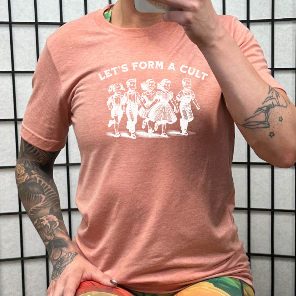 peach shirt with the text "Let's Form A Cult" on it