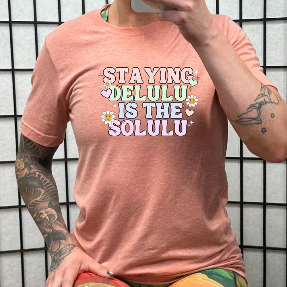 peach shirt with the text "Staying Delulu Is The Solulu" on it