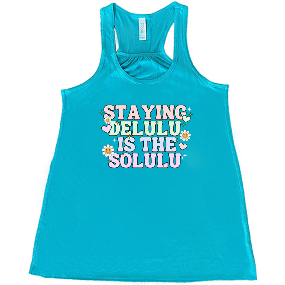 teal shirt with the text "Staying Delulu Is The Solulu" on it