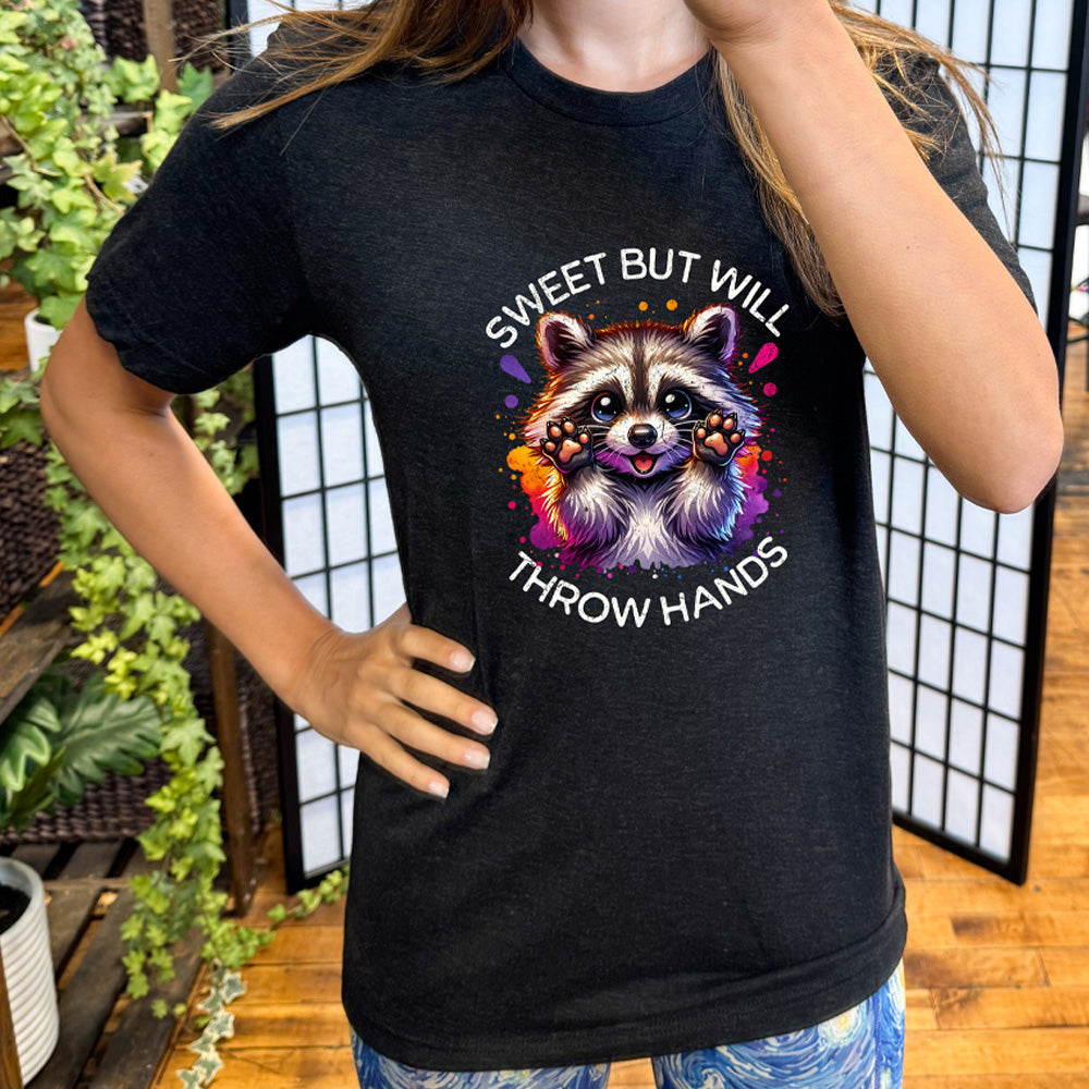 black shirt with the text "Sweet But Will Throw Hands" and a graphic of a raccoon on it