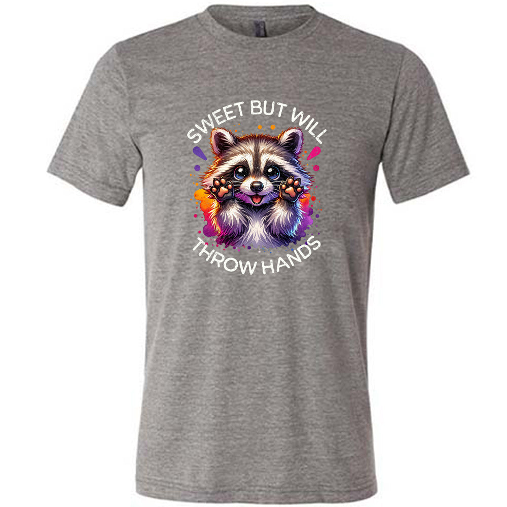 grey shirt with the text "Sweet But Will Throw Hands" and a graphic of a raccoon on it