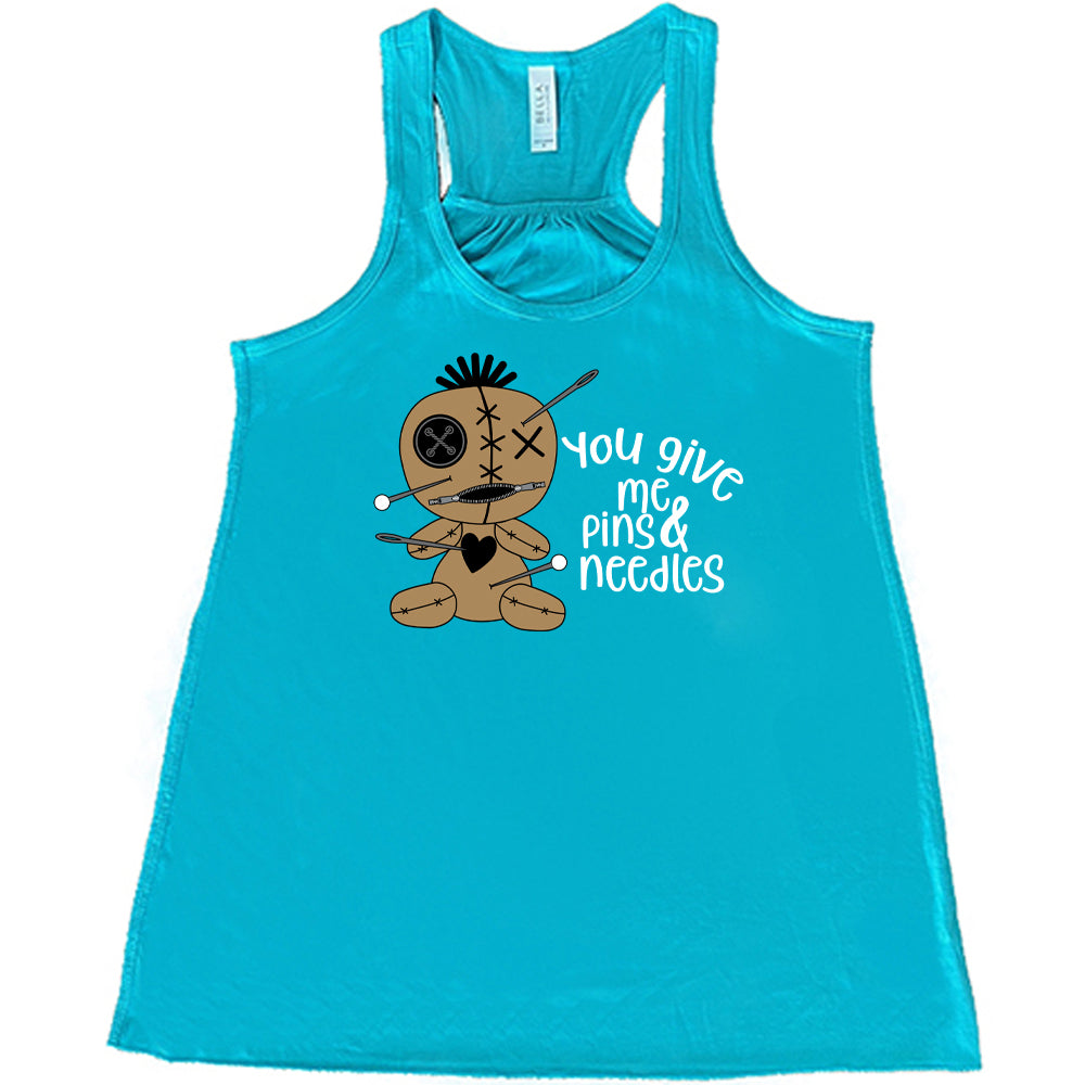 teal shirt with a voodoo doll graphic and the quote "You Give Me Pins And Needles" on it