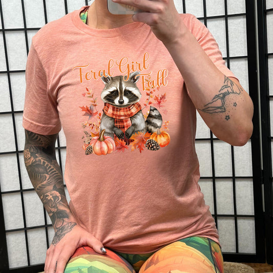 peach "Feral Girl Fall" with a raccoon graphic on it shirt