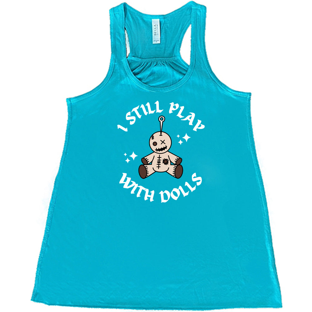 teal shirt that has a voodoo doll graphic and the text "i still play with dolls" on it