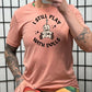 peach shirt that has a voodoo doll graphic and the text "i still play with dolls" on it