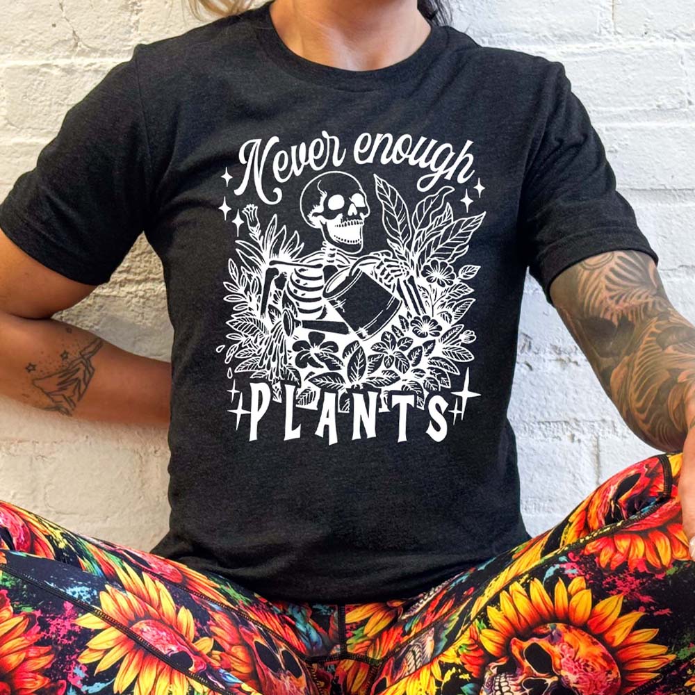 model wearing the black unisex shirt with the saying "Never Enough Plants" and skeleton graphic on it in white