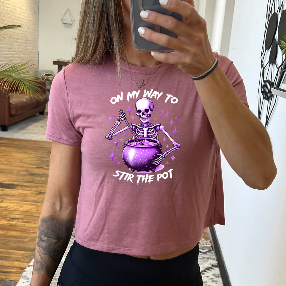 mauve cropped tee with a skeleton graphic and the quote "on my way to stir the pot" on it